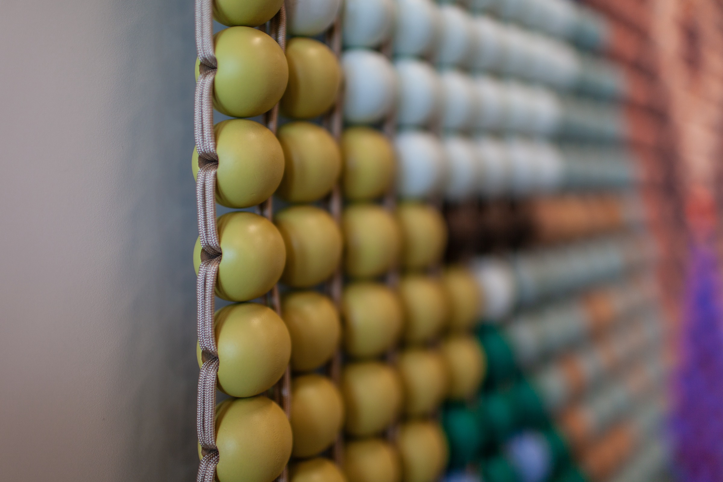 Painted wooden beads strung on cord, bound to one another above and below