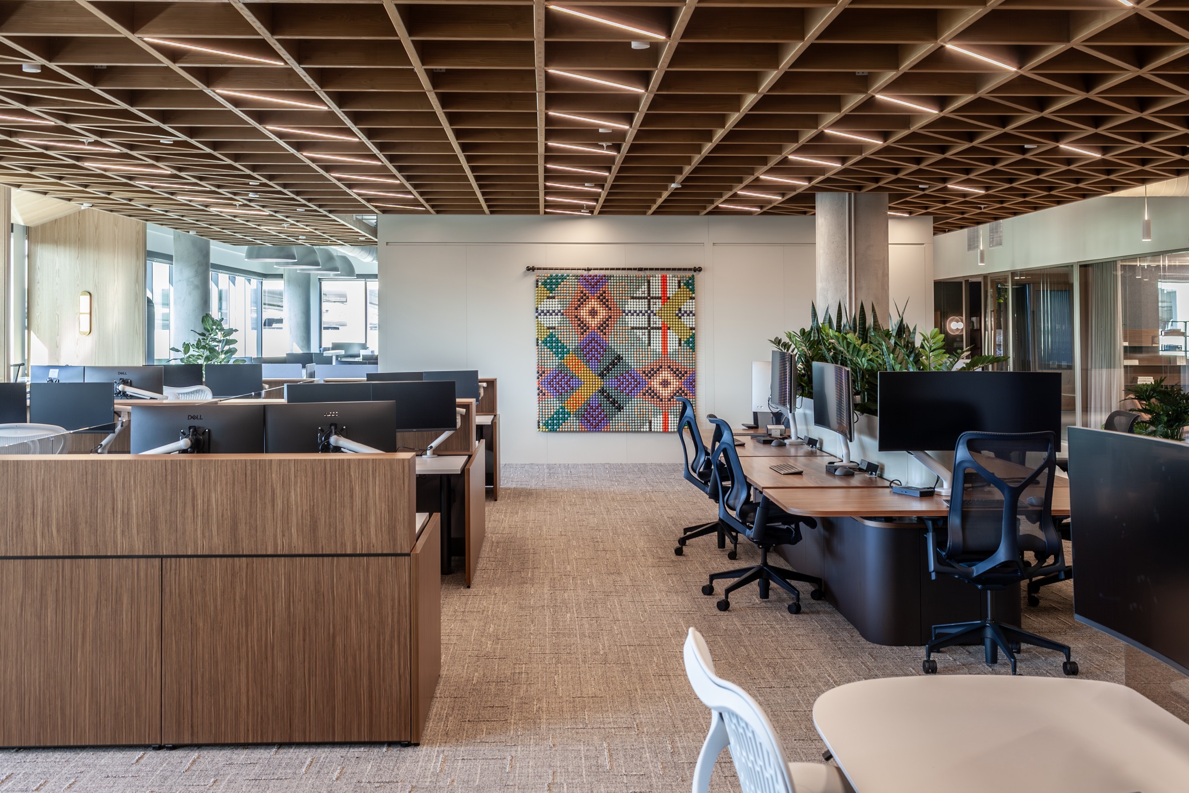 Adam A. Wier's woven bead piece hanging in a bright office under a wooden ceiling